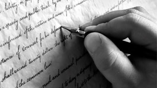 Black and white picture of someone writing on paper using a fountain pen