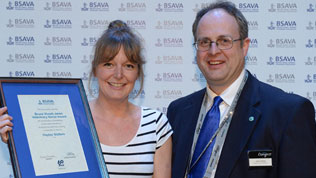 A BSAVA award winner presented with their framed certificate, smiling at the camera