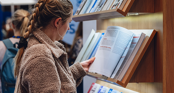 Three people browsing BSAVA's range of printed books and manuals in a specialist bookstore
