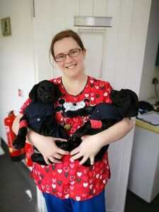 Jody Barry BSc (Hons) RVN holding a pair of black puppies