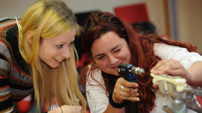 A veterinary student undertaking practical training with a tuitor by her side