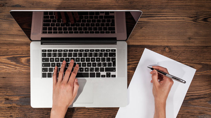 Someone making taking a veterinary CPD online training course and making notes while using an Apple Mac laptop