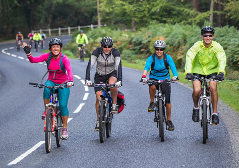 Four cyclists travelling together on a road through the New Forest