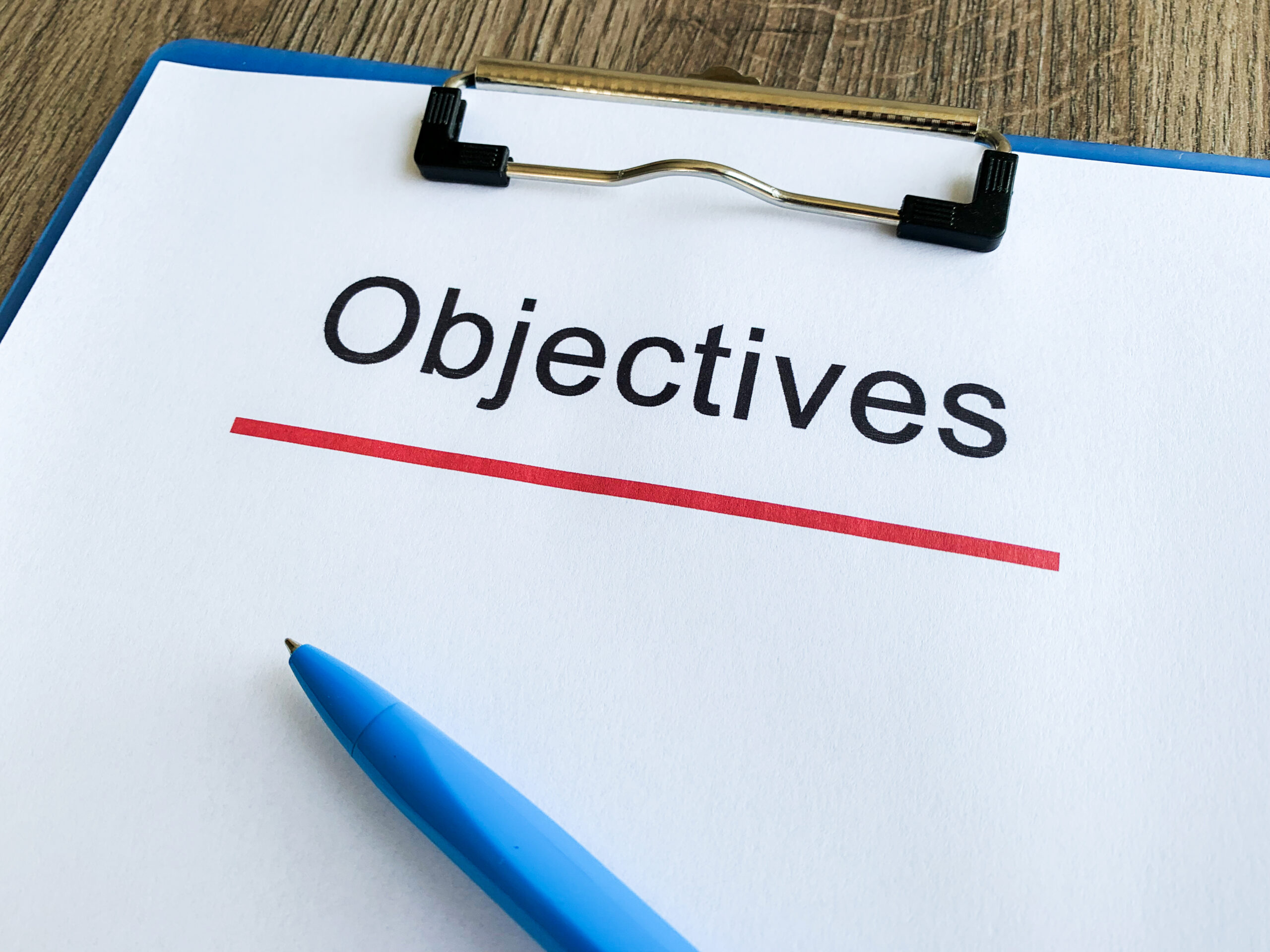 Paper with text 'objective', on a wooden table.